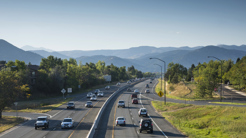 Cars driving on the highway in front of mountains.