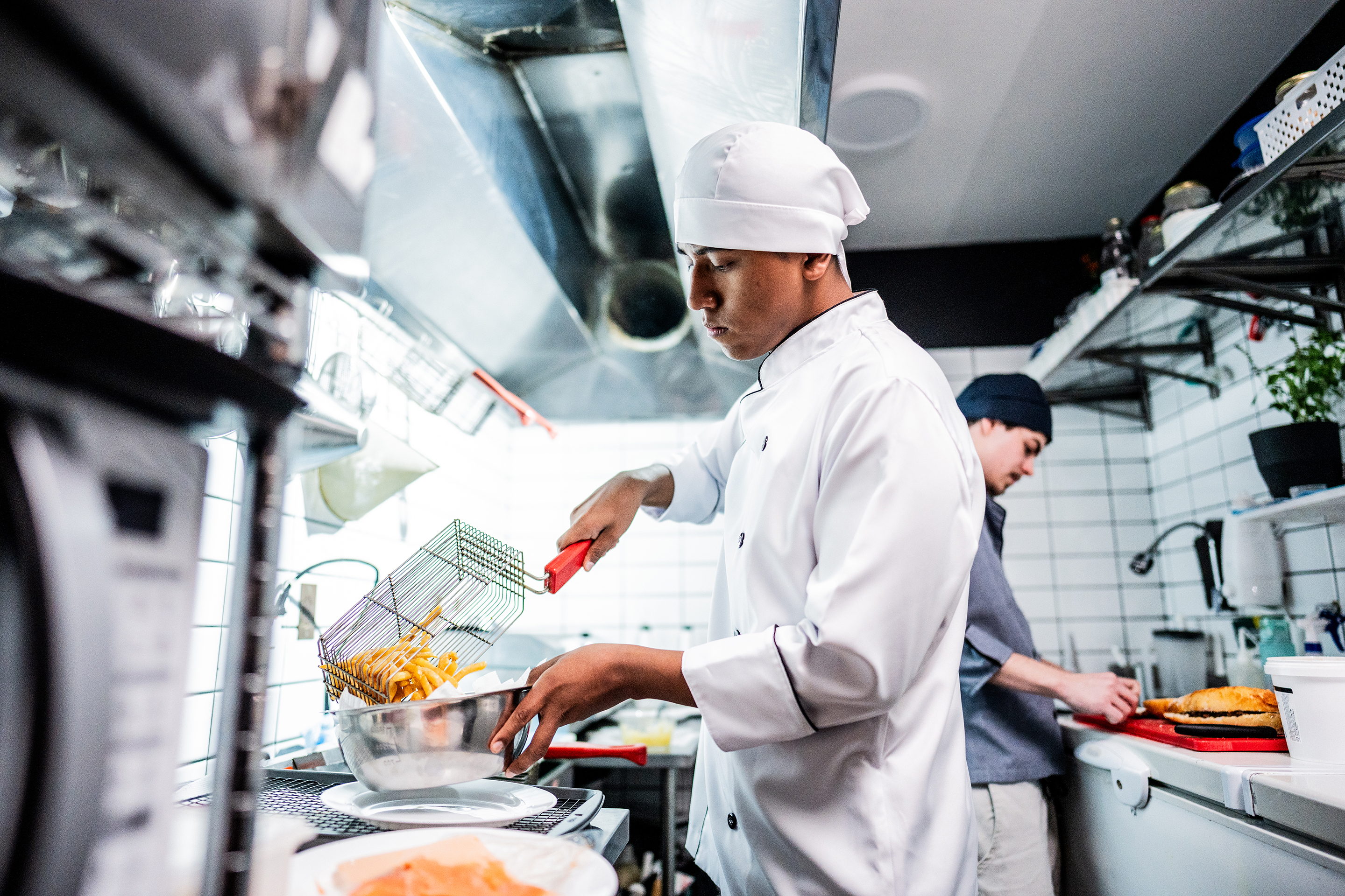 Chef making fries in a commercial kitchen.