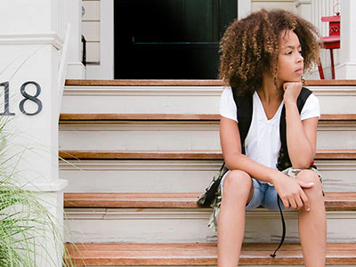 Child sitting in front of house.