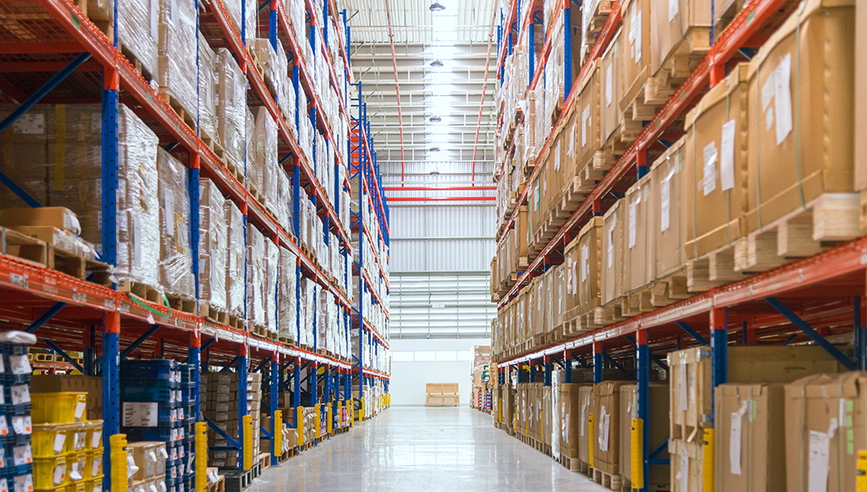 Warehouse hallway filled with shelving filled with boxes and supplies.