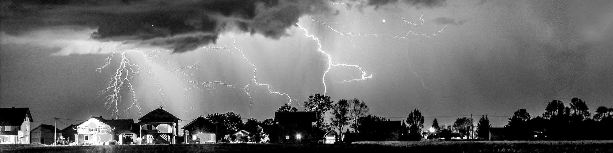 Houses with lightning in the background.