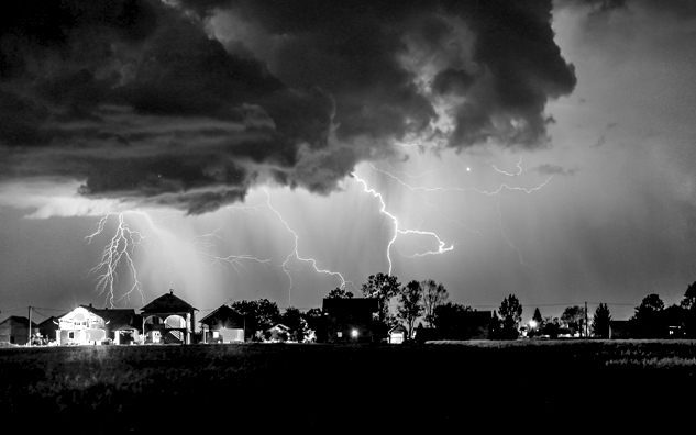 Black and white clouds and thunder strikes over a neighborhood