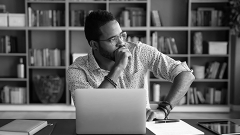 Man sitting at a desk in front of laptop searching for home insurance.