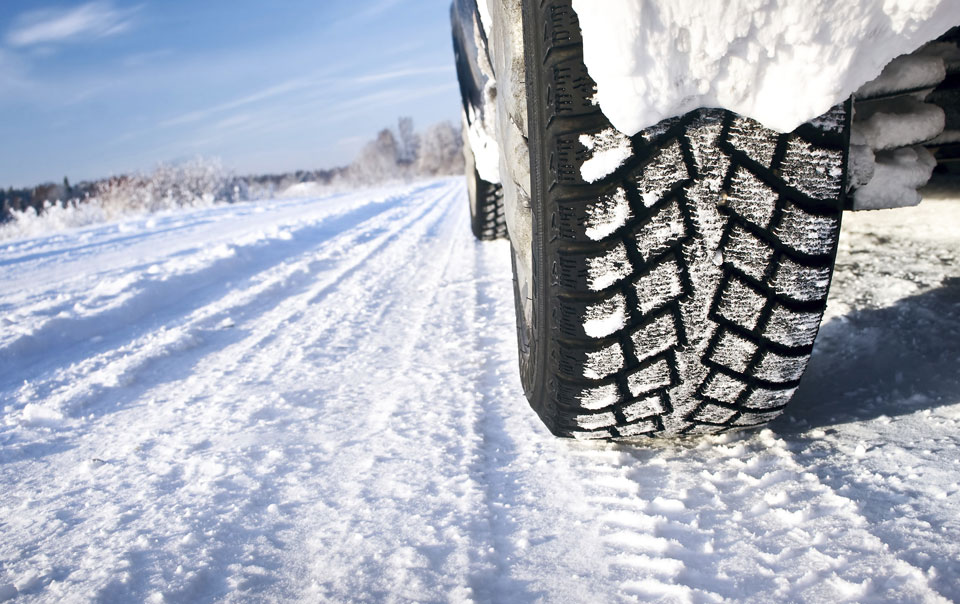 Close-up of snow tires on snow-covered road.