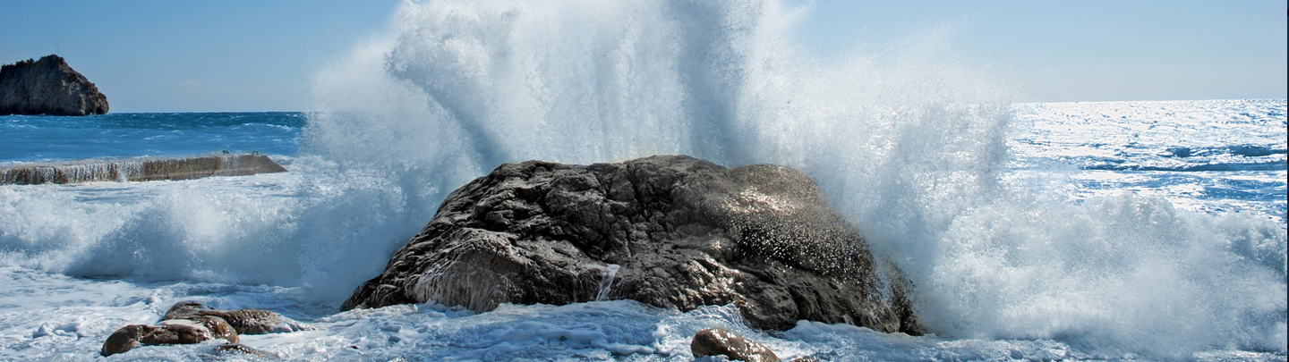 Ocean waves crash over a large rock