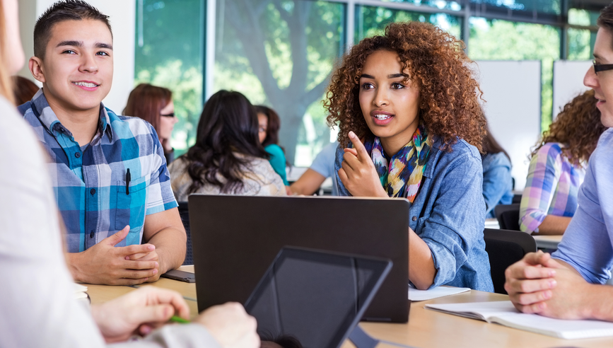 A woman on her laptop sitting at table next to a male.