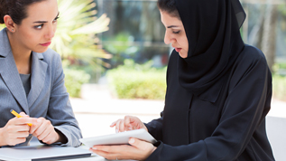 Two women have a conversation at a table outdoor