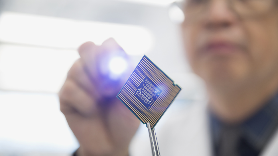 Focused engineer examining microchip with flashlight