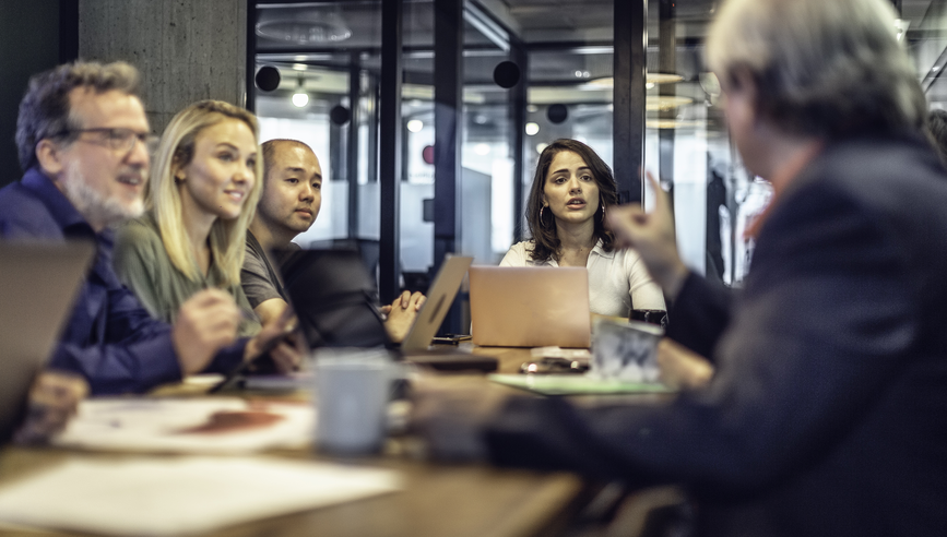 Multi-ethnic group of business people discussing ideas at a conference table in a modern office.