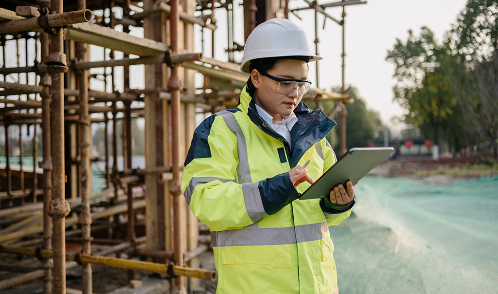 Female construction worker at job site looking at tablet.