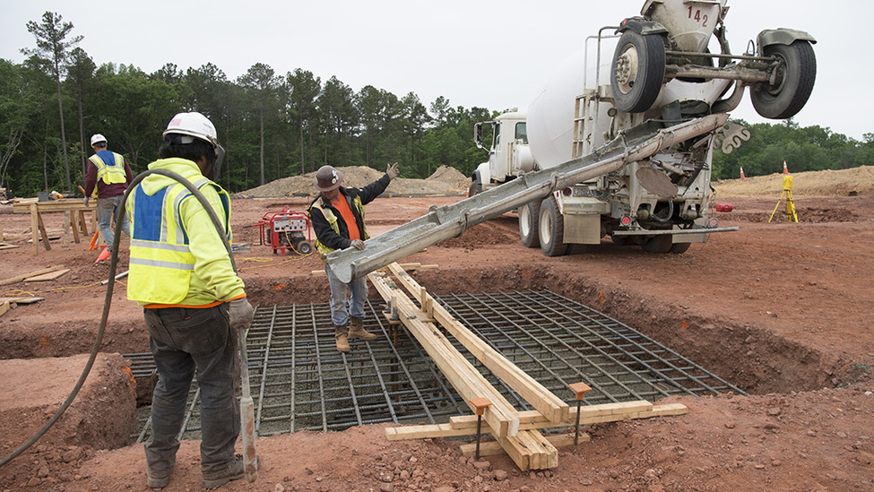 Construction workers pouring concrete at a construction site.