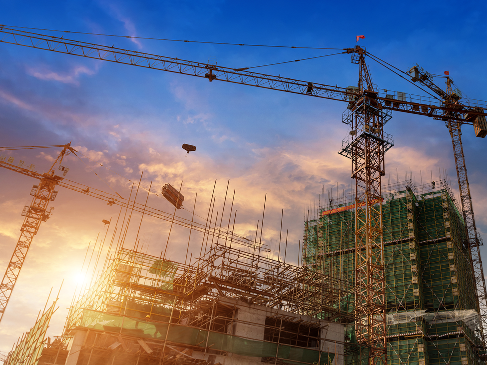 A large construction crane is seen against a colorful dusk sky.