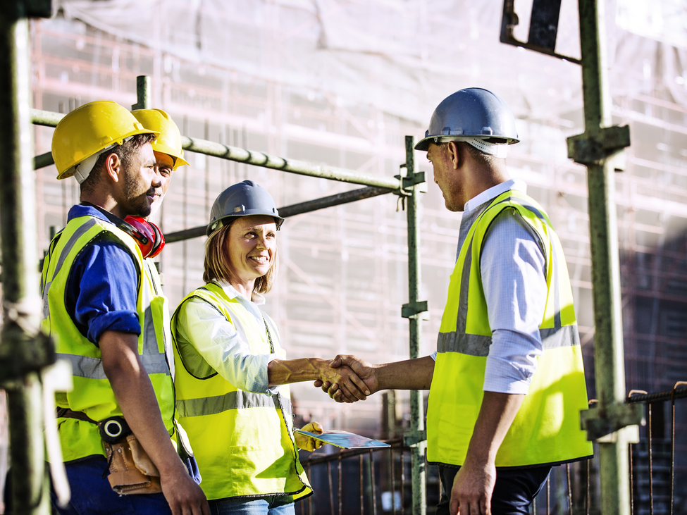 Male and female architects shaking hands at construction site