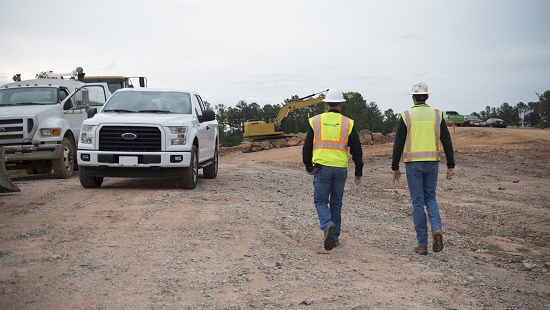 Two construction workers at a construction site walking to their truck.