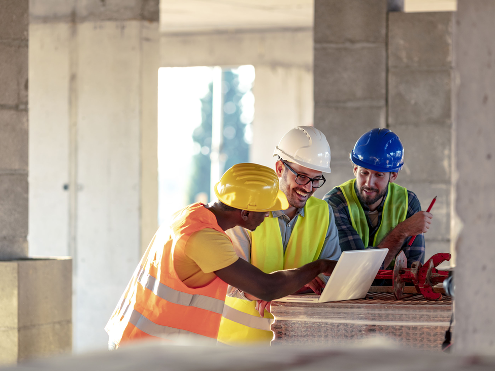 construction workers reviews project on computer.