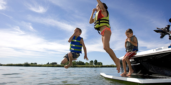 Three children safely jumping into water from a boat.