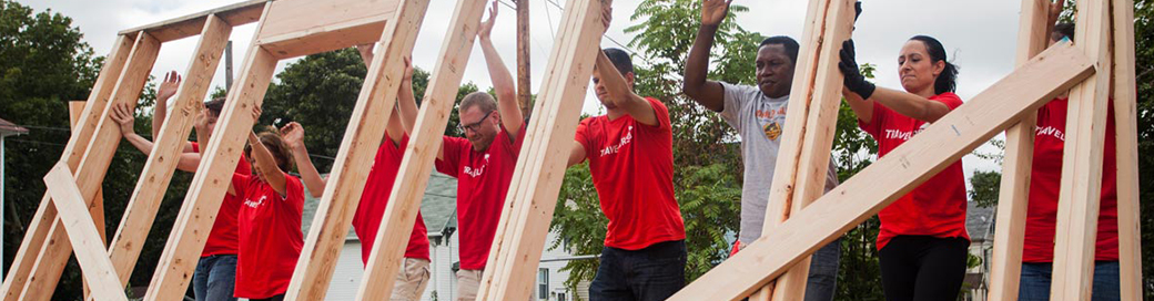 Travelers volunteers lifting up newly constructed wall.