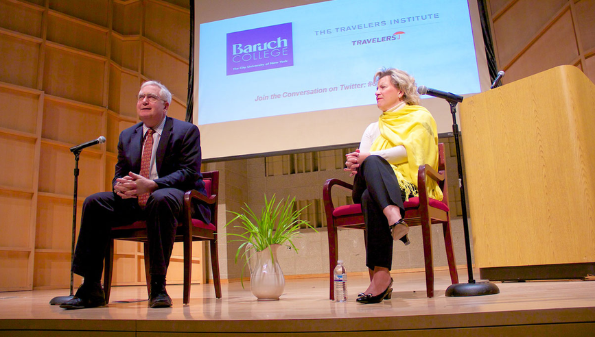 Travelers Institute President Joan Woodward and Baruch College Associate Professor Daniel Williams speaking on stage