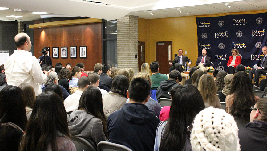 Four person panel speaking in front of crowd of students