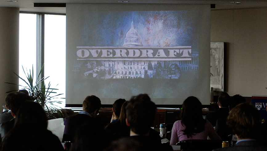 Journalists watch Overdraft documentary on a projector in New York City.