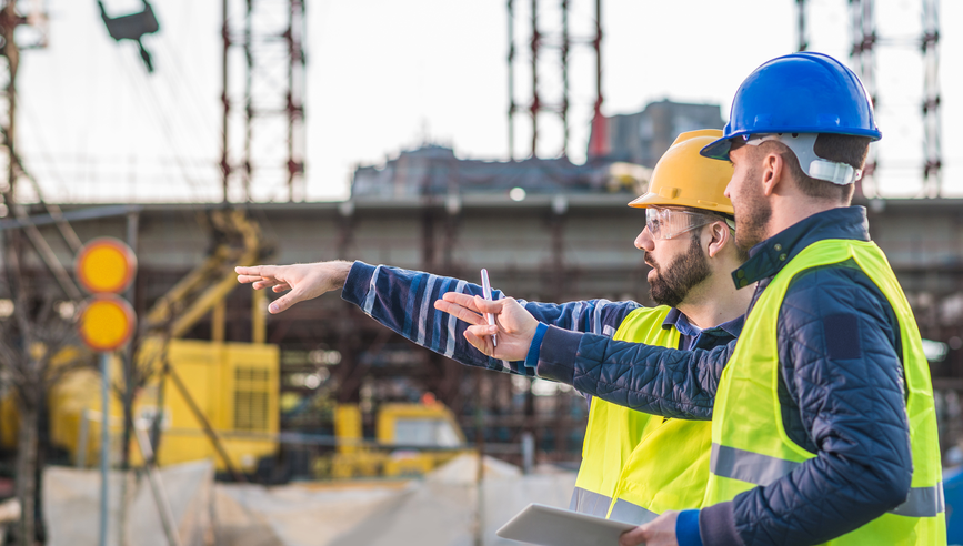 Contractors with blueprints having a meeting on a construction site.