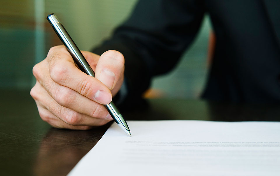 Man holding pen signing contract.