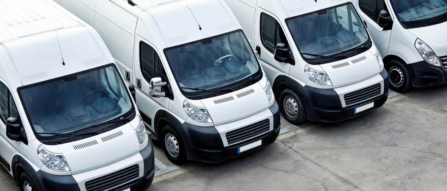 A row of business vans parked in a parking lot.