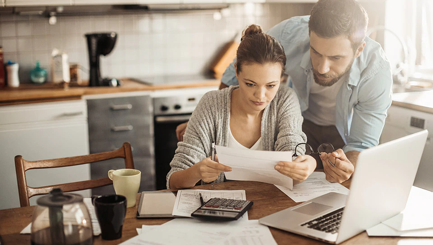 Couple at desk looking at closing cost papers.