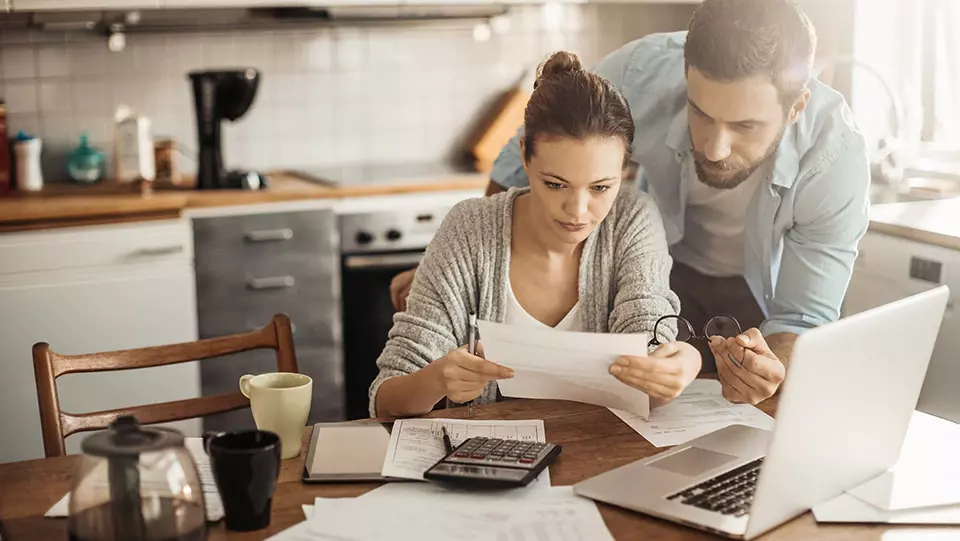 Couple calculating home closing costs in kitchen.