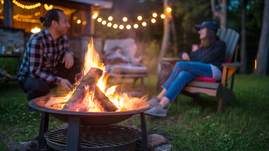 A couple enjoying their time next to a fire pit in a backyard.