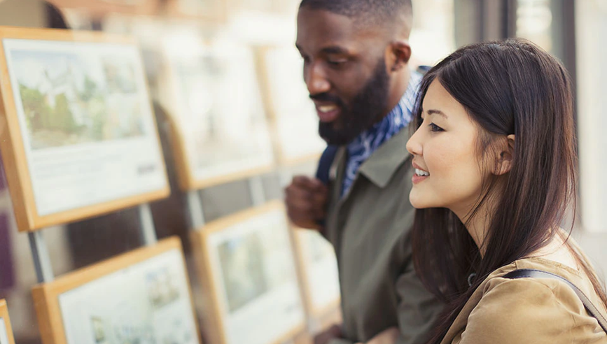 Man and woman looking ads for houses to buy or rent.