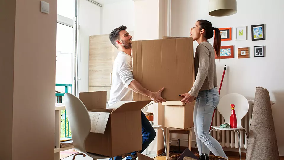 Couple moving boxes themselves into new apartment.