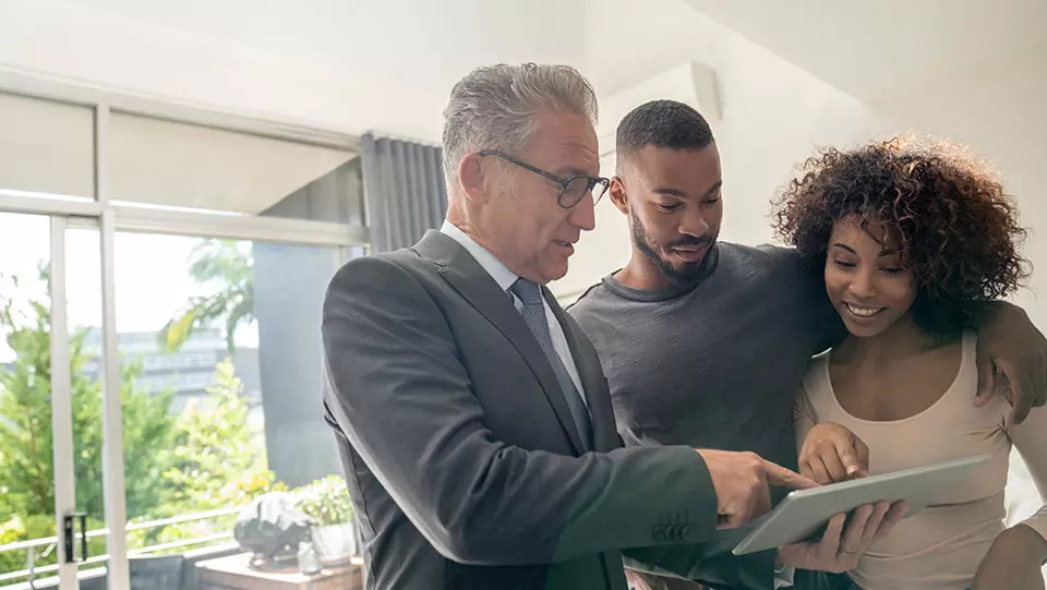 Couple filling out home insurance papers with agent.