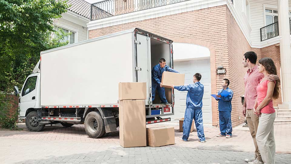 Couple watching moving company move boxes.