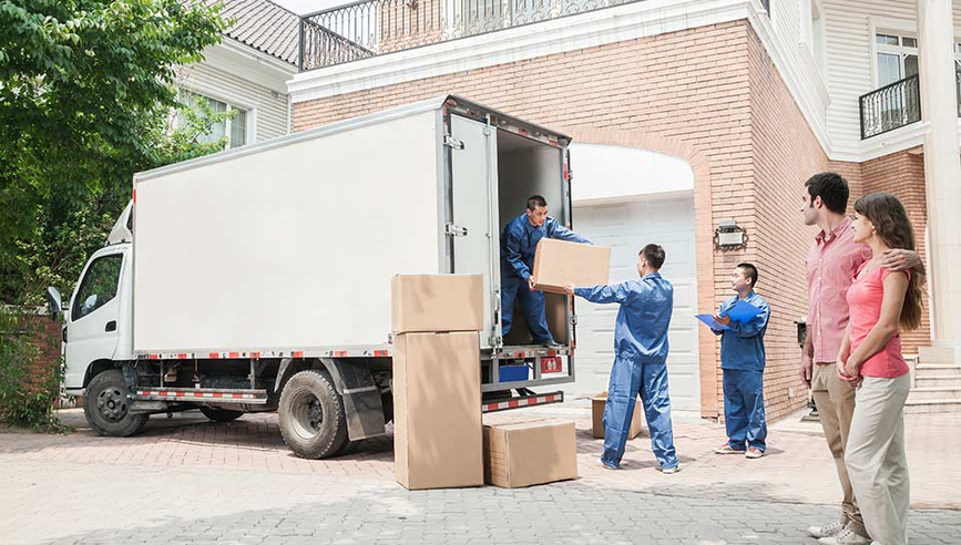 couple watching moving company move boxes