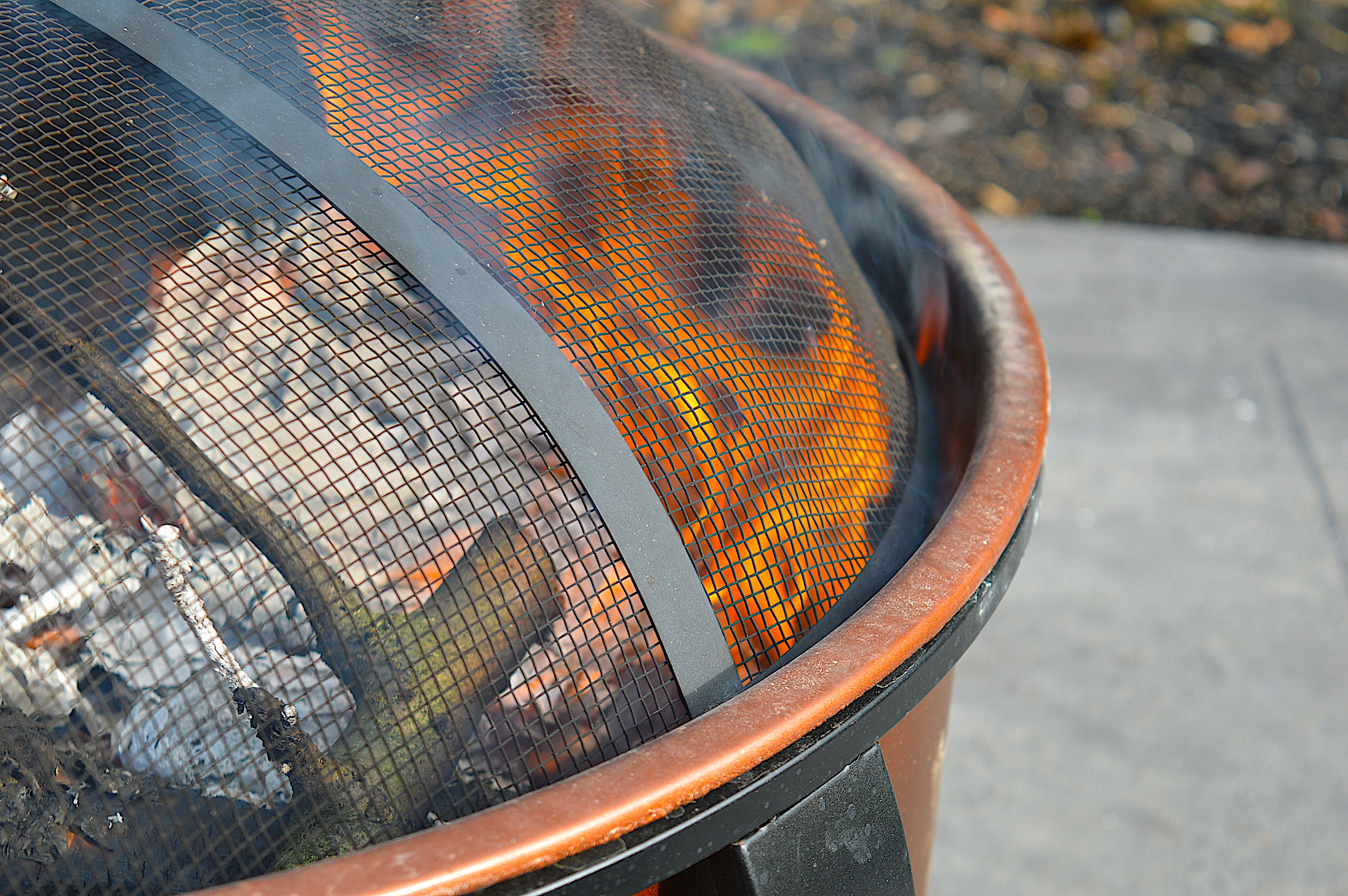 a fire pit in a backyard, covered by a mesh wire screen