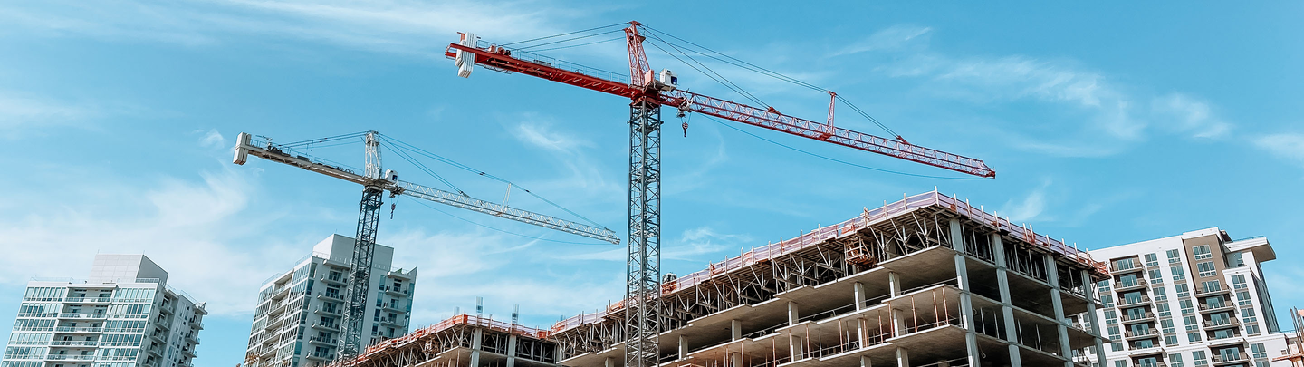 Two cranes high above a building under construction.