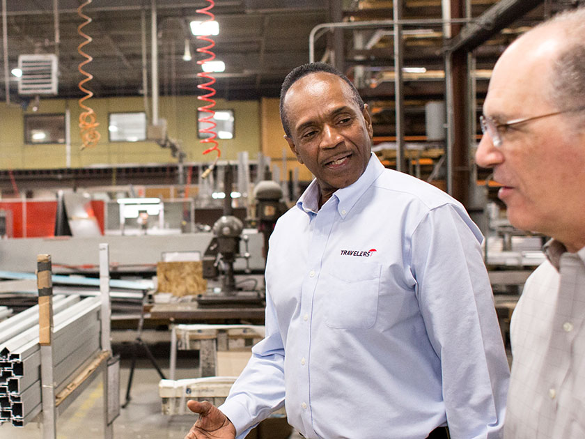 Two men talk in a factory.