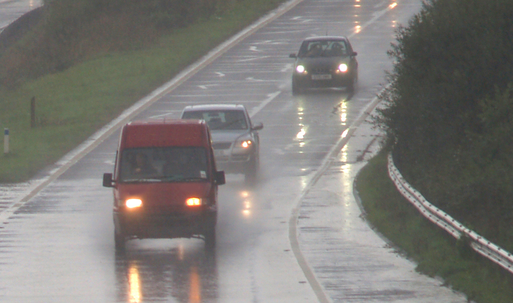 Cars and truck driving cautiously in rain.