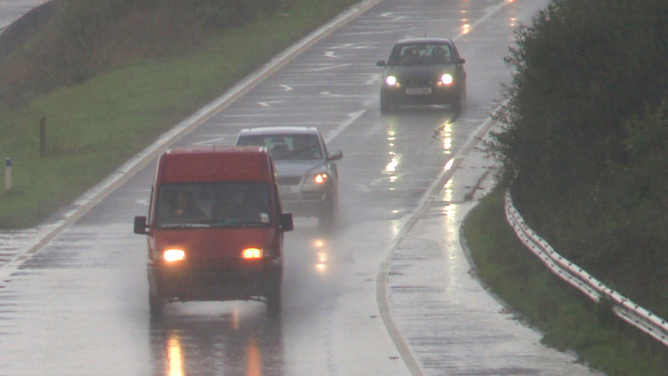 Cars and truck driving cautiously in rain.