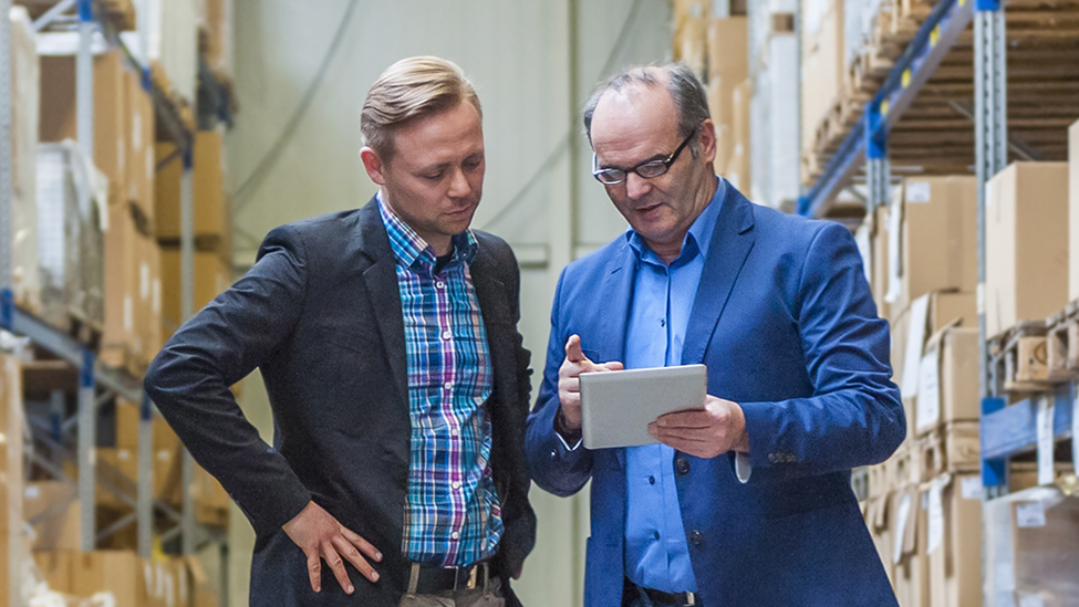 Two men talking in a warehouse.