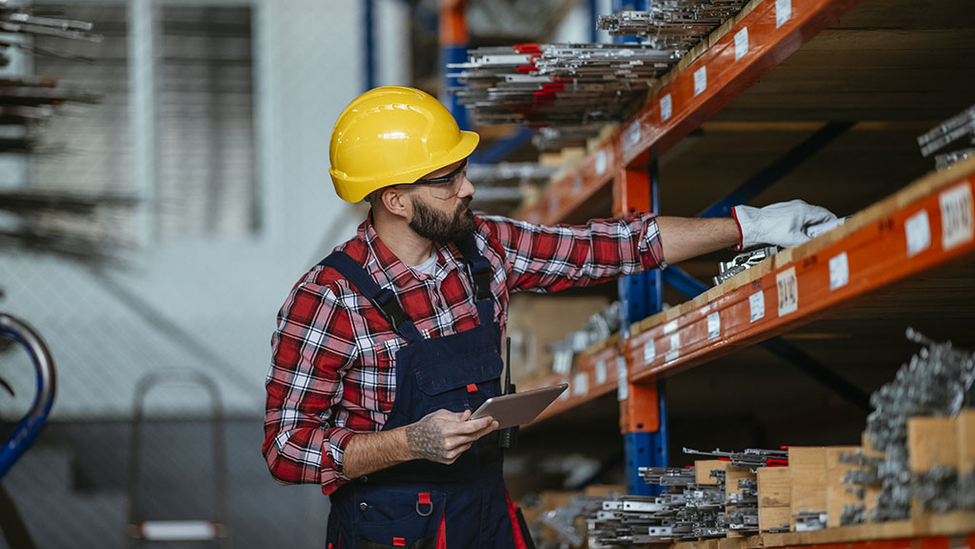 A warehouse worker putting metals away on a multi-shelves unit