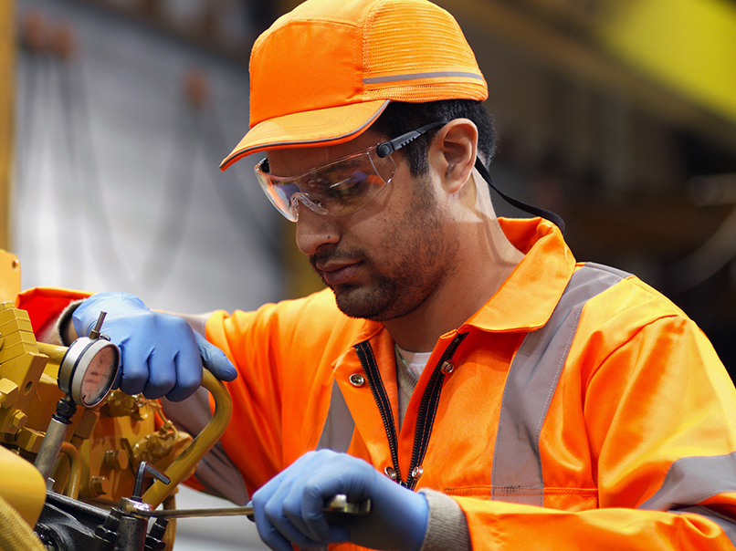 Manufacturing worker fixing a machine with a tool