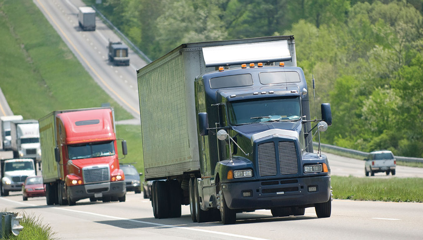 Dark blue large commercial truck driving along an interstate highway