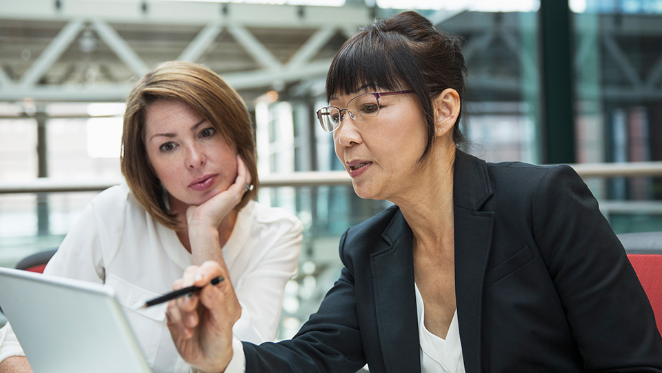 Two women look at a laptop