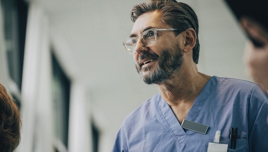 Medical professional wearing blue scrubs, engaged in conversation.