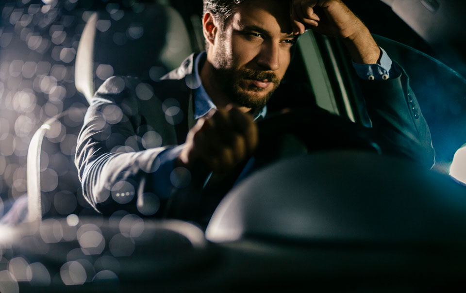 Driver falling asleep behind wheel of car at night.