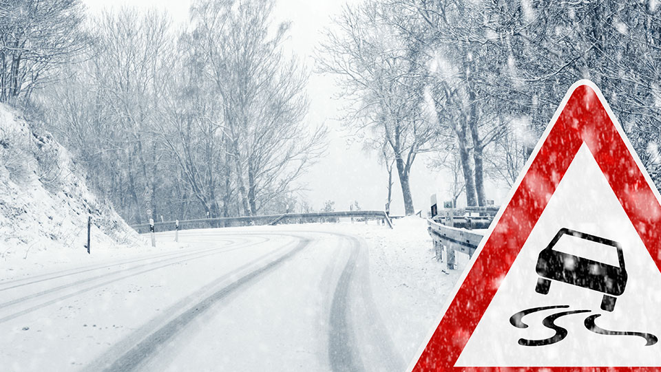 Winding road with snow and ice red hazard sign.