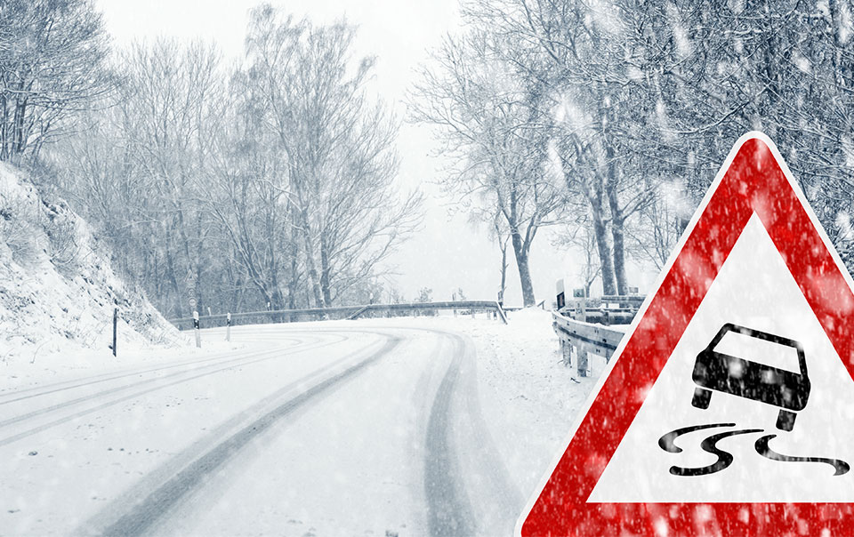 Winding road with snow and ice red hazard sign.