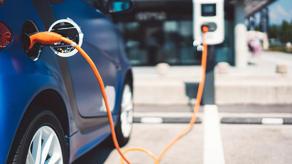 Parked electric car plugged in at charging station.